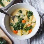 white bowl with potato kale soup and spoon.