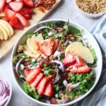 bowl with strawberry apple salad surrounded by ingredients to make the salad.