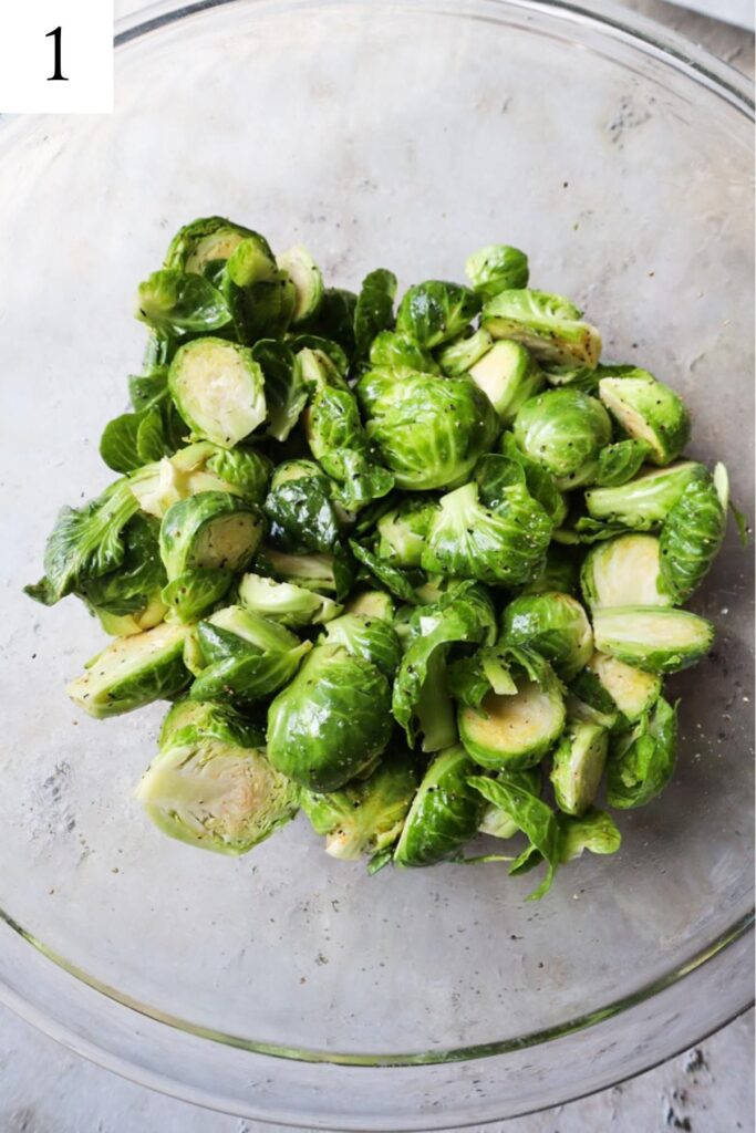 glass bowl with brussels sprouts tossed with olive oil, salt, and pepper.