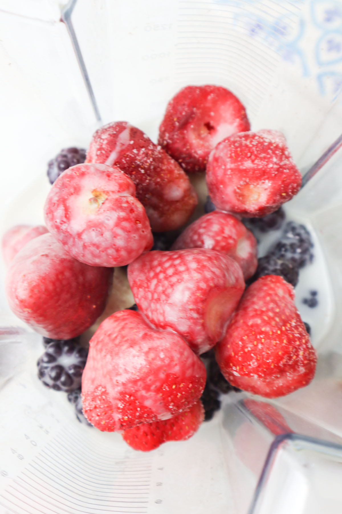 blender with frozen strawberries and blackberries. 