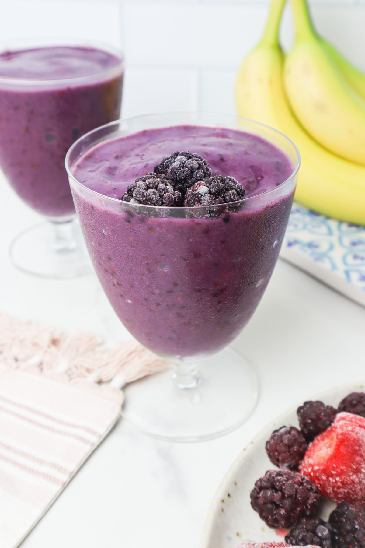 blackberry strawberry smoothie in a glass with frozen blackberries. 