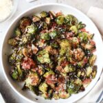 white bowl with brussels sprouts, parmesan cheese, prosciutto, and balsamic glaze.