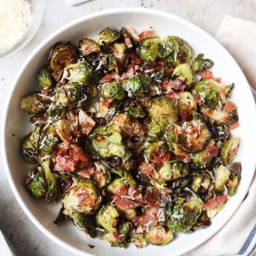 white bowl with brussels sprouts, parmesan cheese, prosciutto, and balsamic glaze.