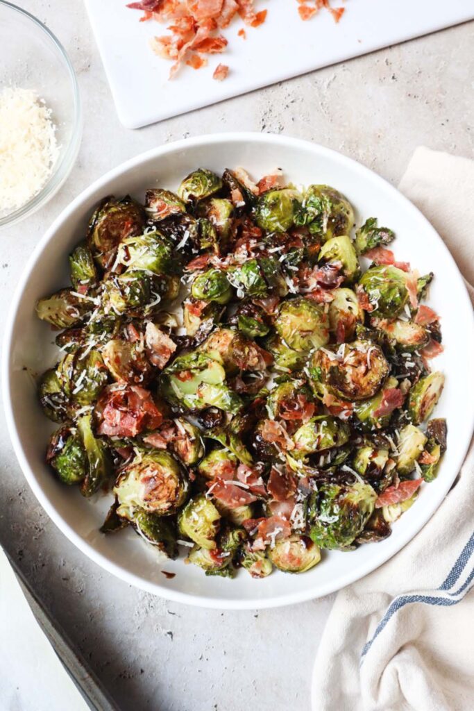 white bowl with brussels sprouts, parmesan cheese, prosciutto, and balsamic glaze.