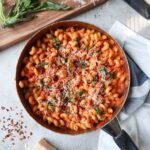 skillet with vodka sauce topped with parmesan and basil.