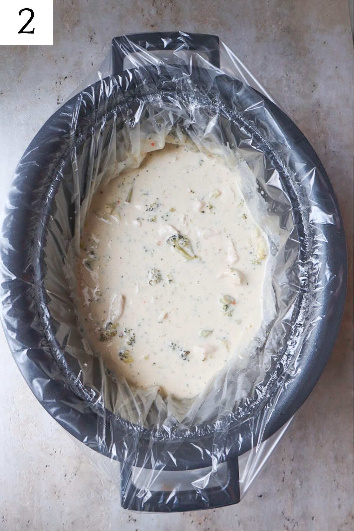 crock pot with alfredo sauce and broccoli.