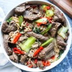 white plate with noodles, vegetables, and beef.