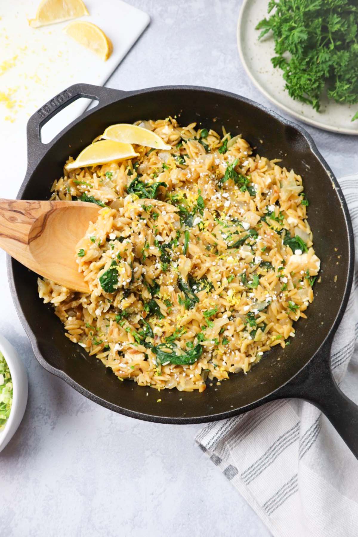 skillet with lemon orzo topped with parsley and feta cheese.
