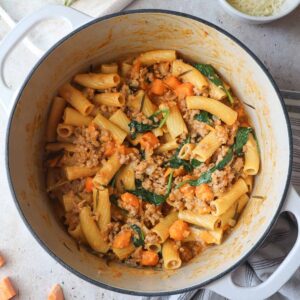 pot with creamy ground pork pasta with sweet potato and spinach.