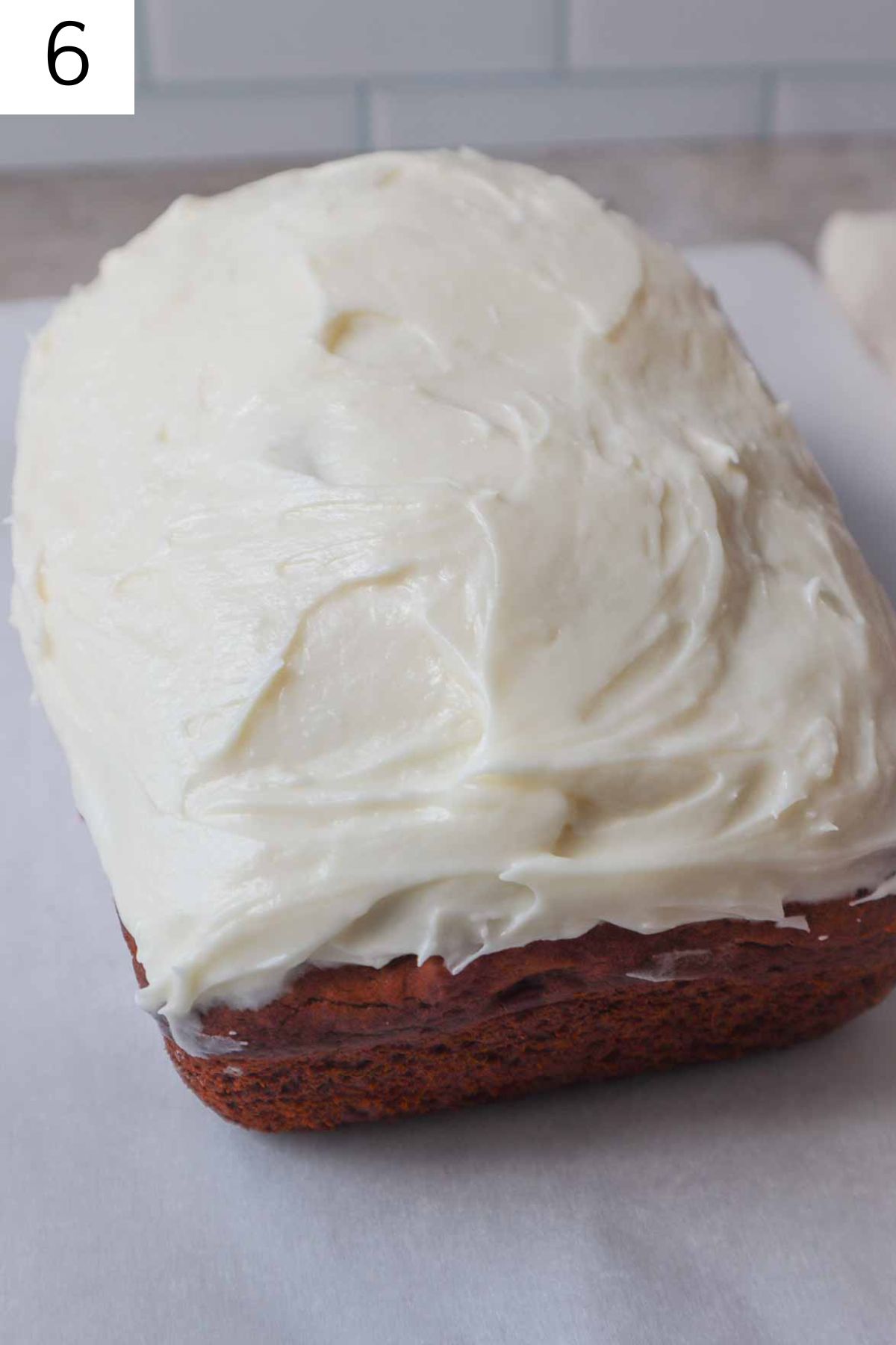loaf of frosted pumpkin bread on a cutting board.