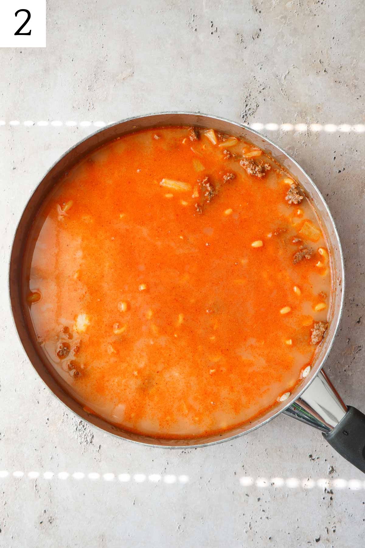 skillet with ground beef, macaroni, broth, and tomato sauce.