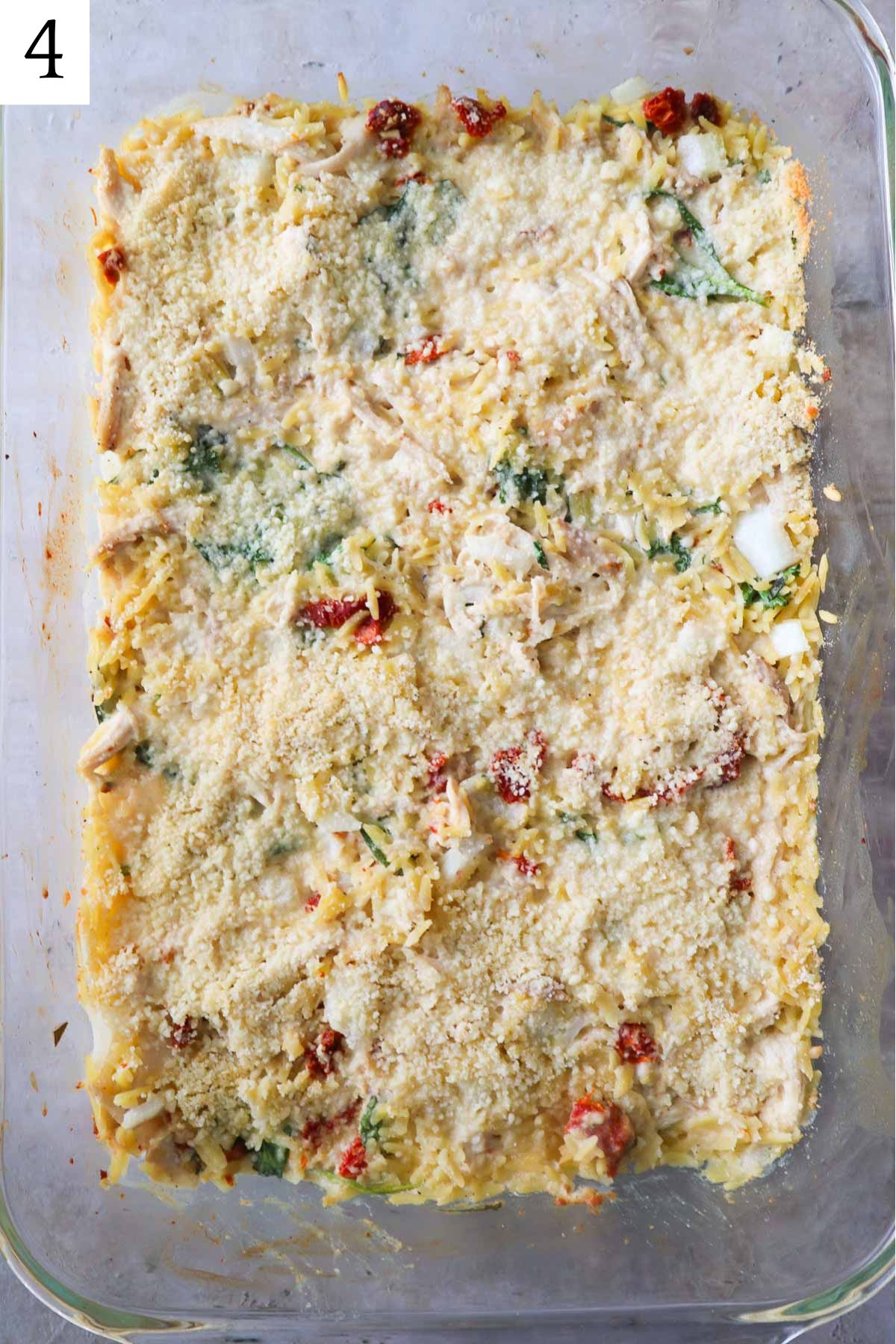 glass baking dish with orzo topped with parmesan cheese.