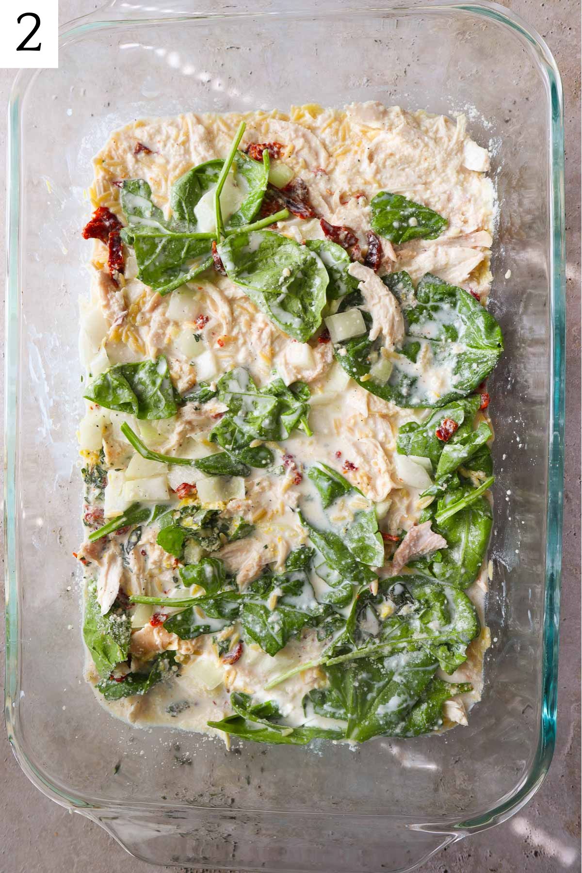 glass baking dish with creamy orzo with spinach, chicken, and sundried tomatoes.