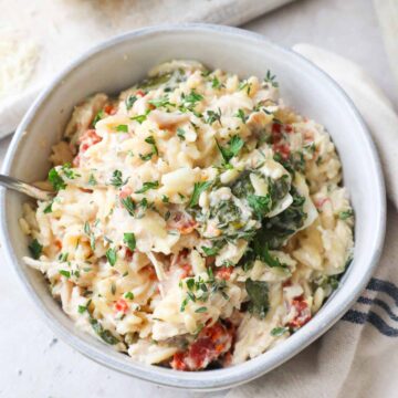 glass bowl with baked chicken orzo pasta topped with parsley.
