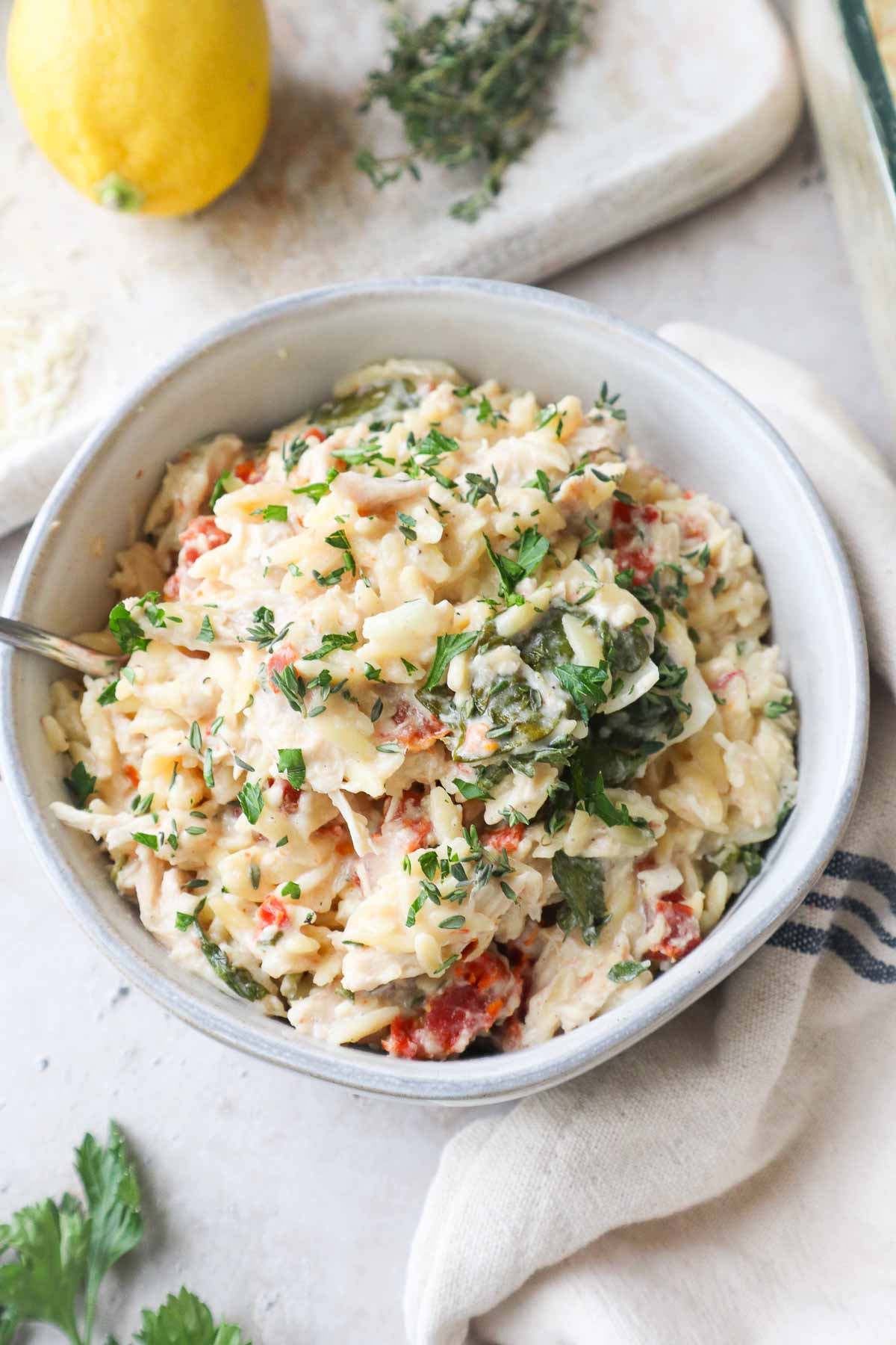 glass bowl with baked chicken orzo pasta topped with parsley.