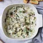 baking dish with creamy boursin cheese dip surrounded by crostinis.