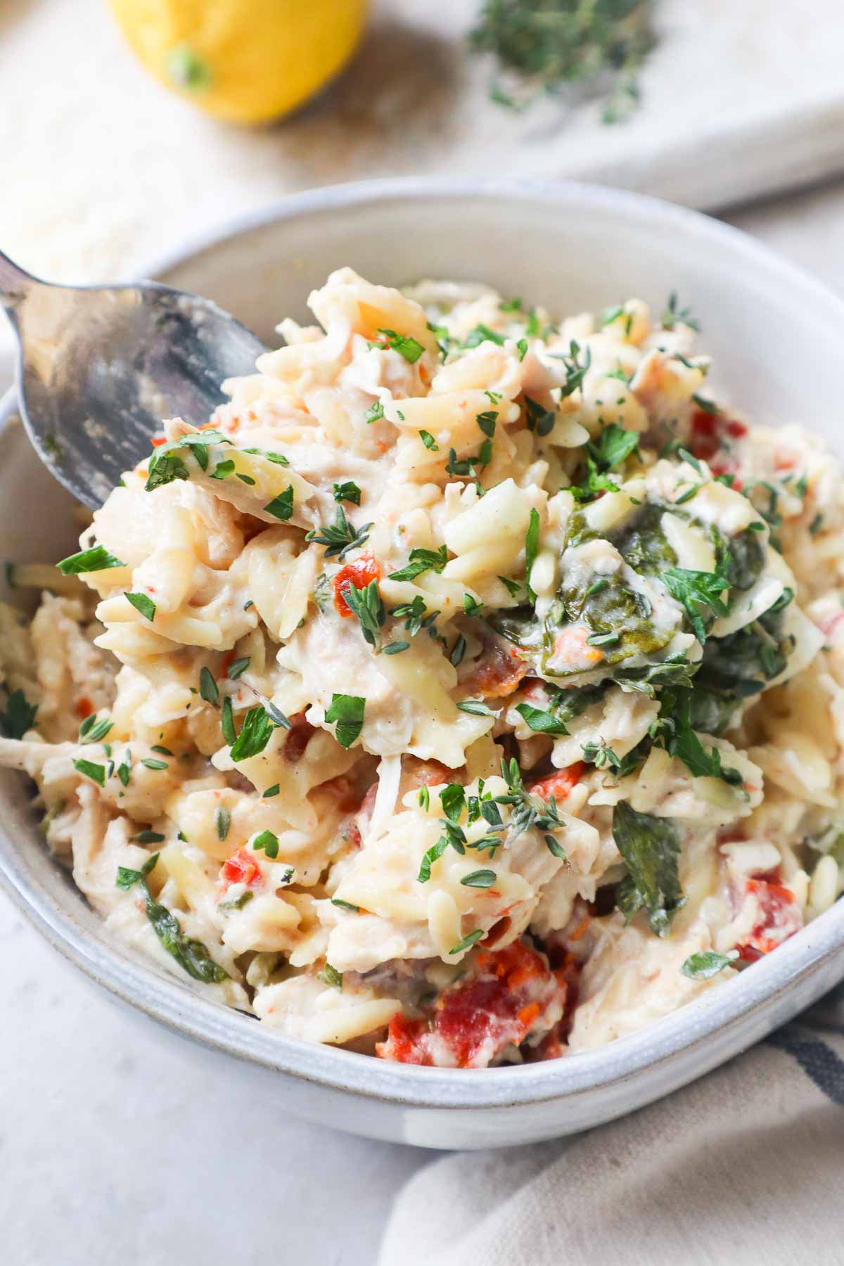 glass bowl with baked chicken orzo pasta topped with parsley.