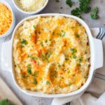 baked cheesy mashed potatoes with garlic in a baking dish topped with parsley.