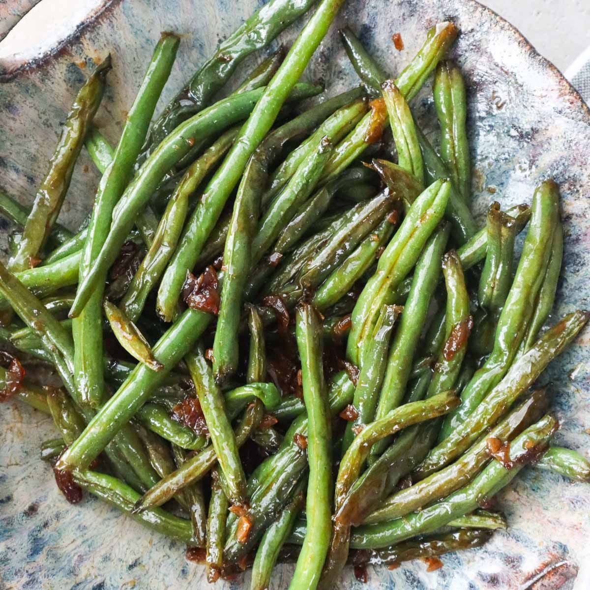 plate with honey garlic green beans tossed in sauce.