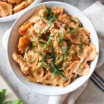 white bowl with chicken ricotta pasta topped with fresh basil.