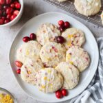 white plate with orange cranberry cookies with cranberries.