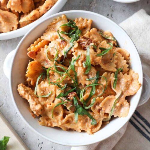 bowl with creamy chicken ricotta pasta topped with fresh basil.