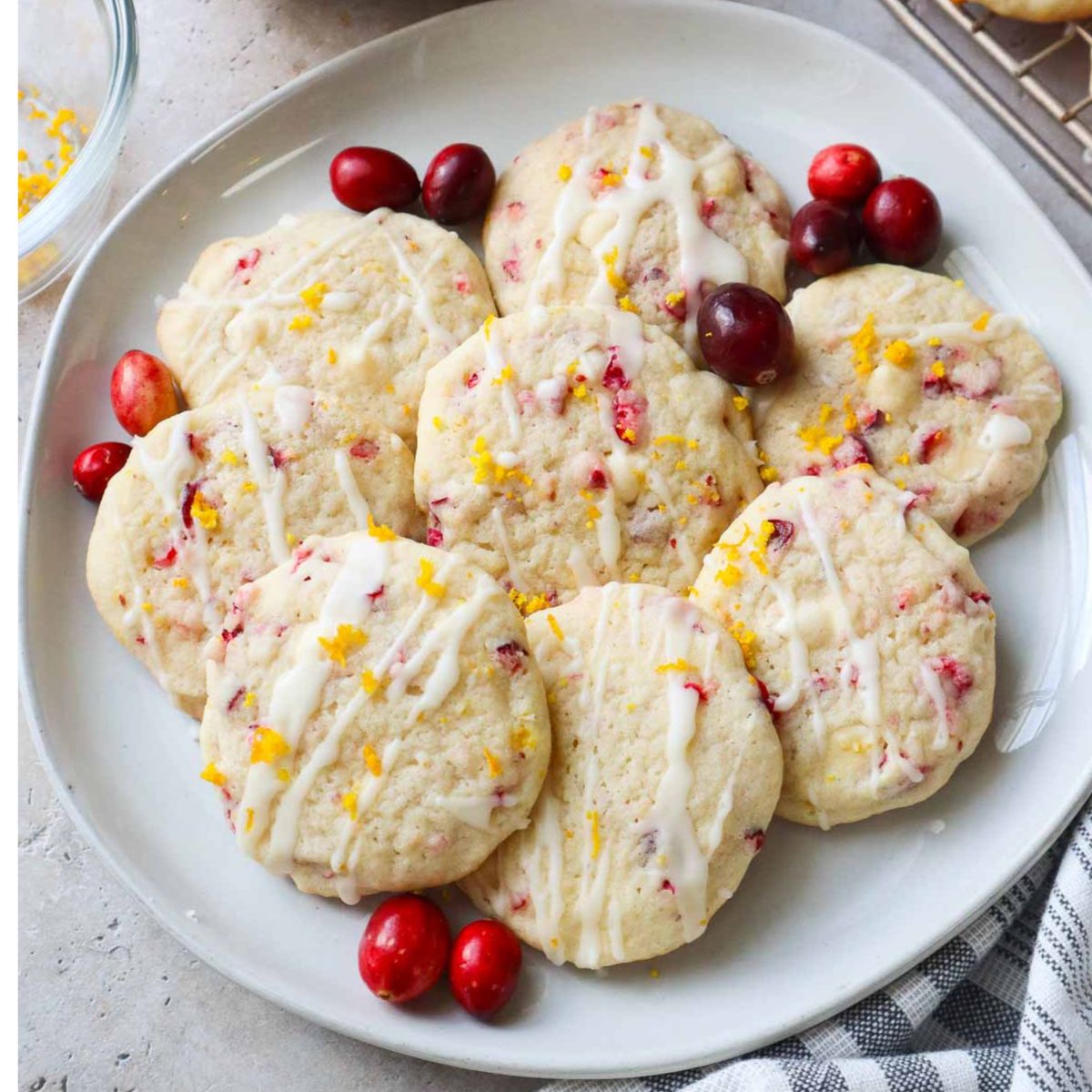 white plate with orange cranberry cookies with cranberries.