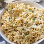 plate with roasted garlic pasta topped with parmesan and parsley.
