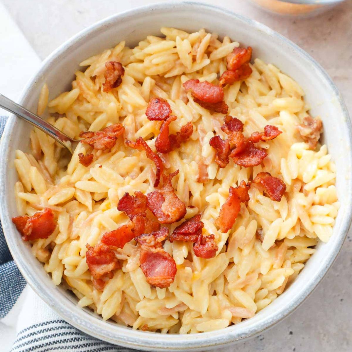 bowl with orzo mac and cheese topped with bacon.