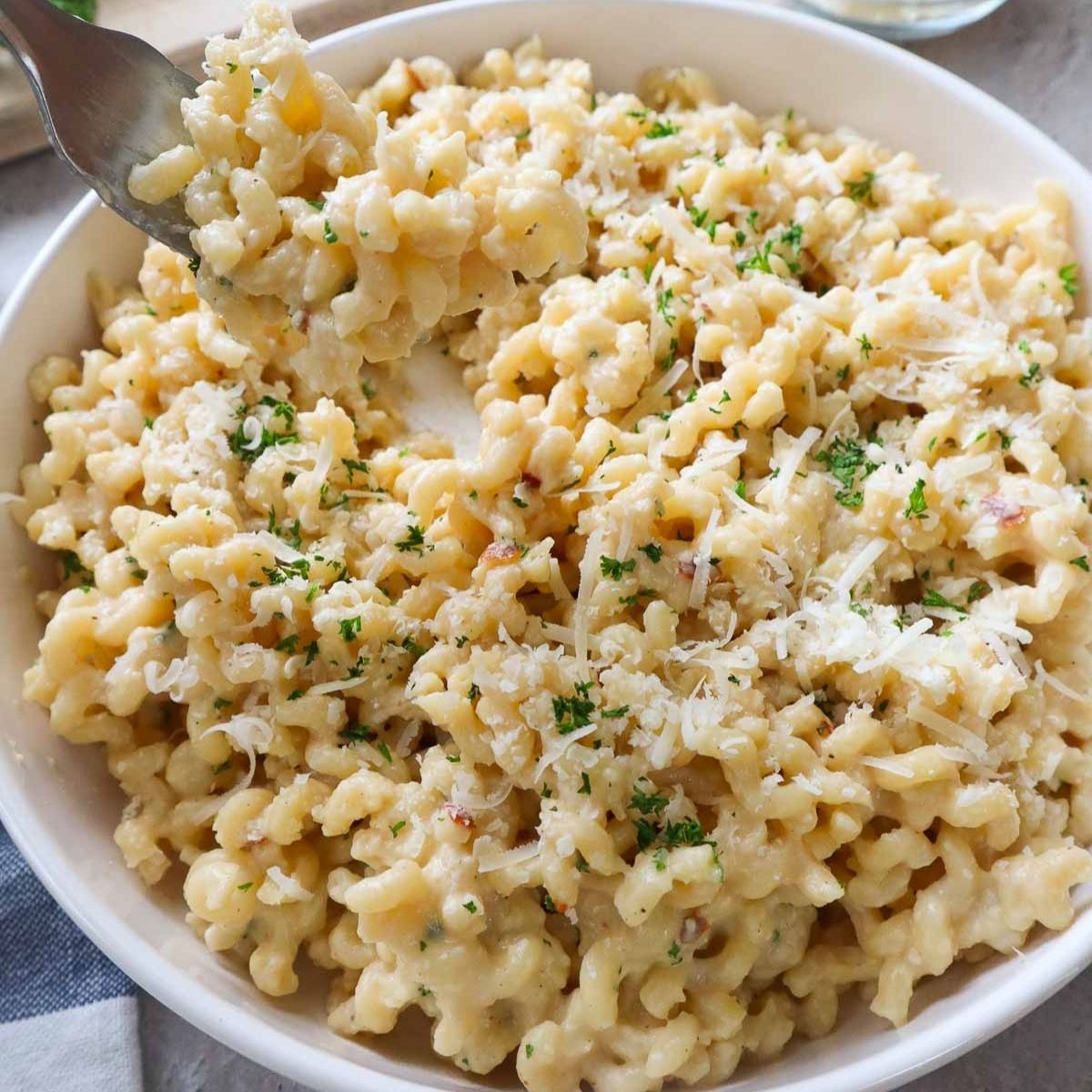 plate with roasted garlic pasta topped with parmesan and parsley.