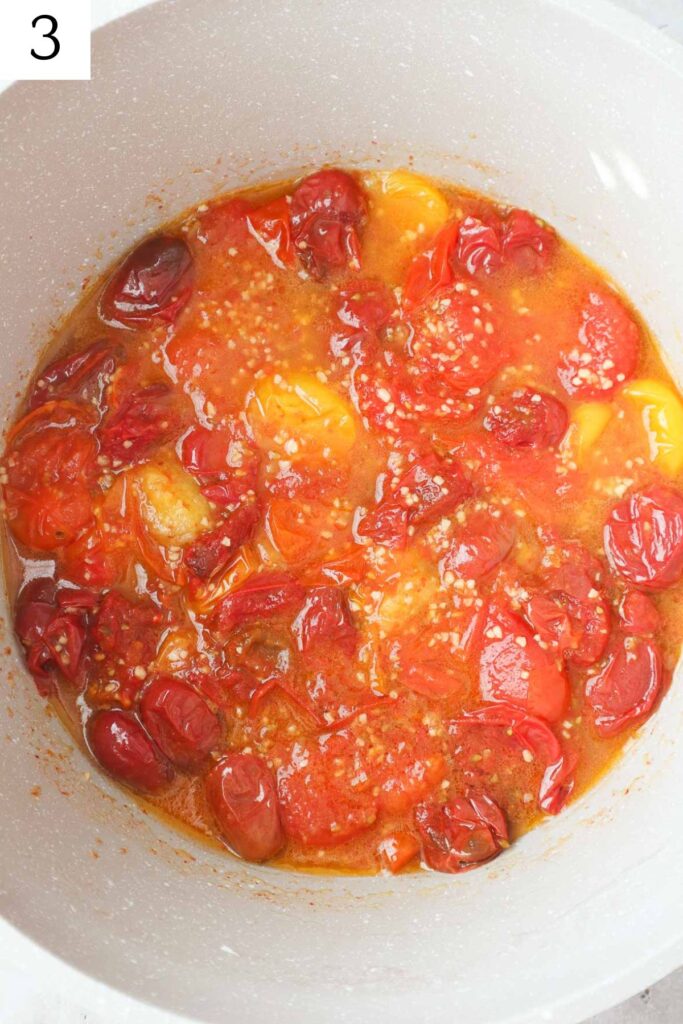 pot with cherry tomatoes and garlic cooked down.