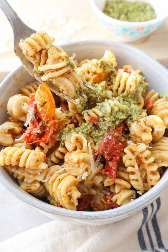bowl with pesto and cherry tomato sauce topped with parmesan.