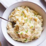 white bowl with boursin mashed potatoes topped with green onion.