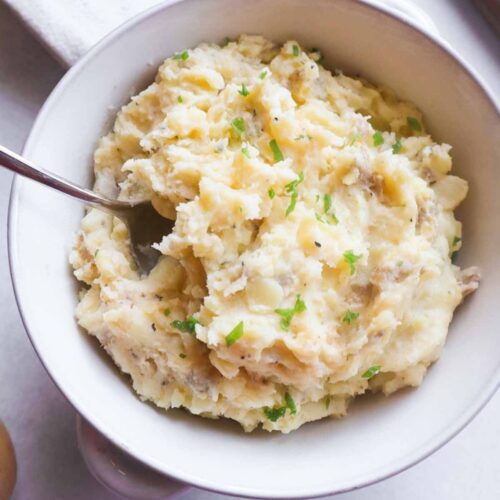 white bowl with boursin mashed potatoes topped with green onion.