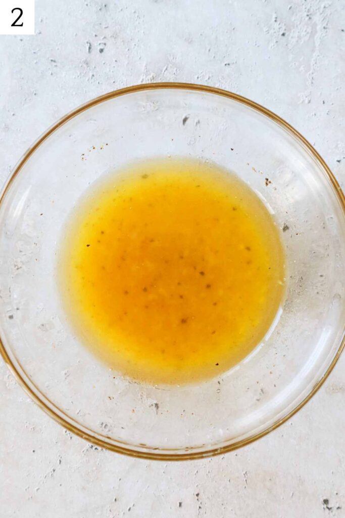 glass bowl with ingredients to make the lemon honey dressing whisked together.