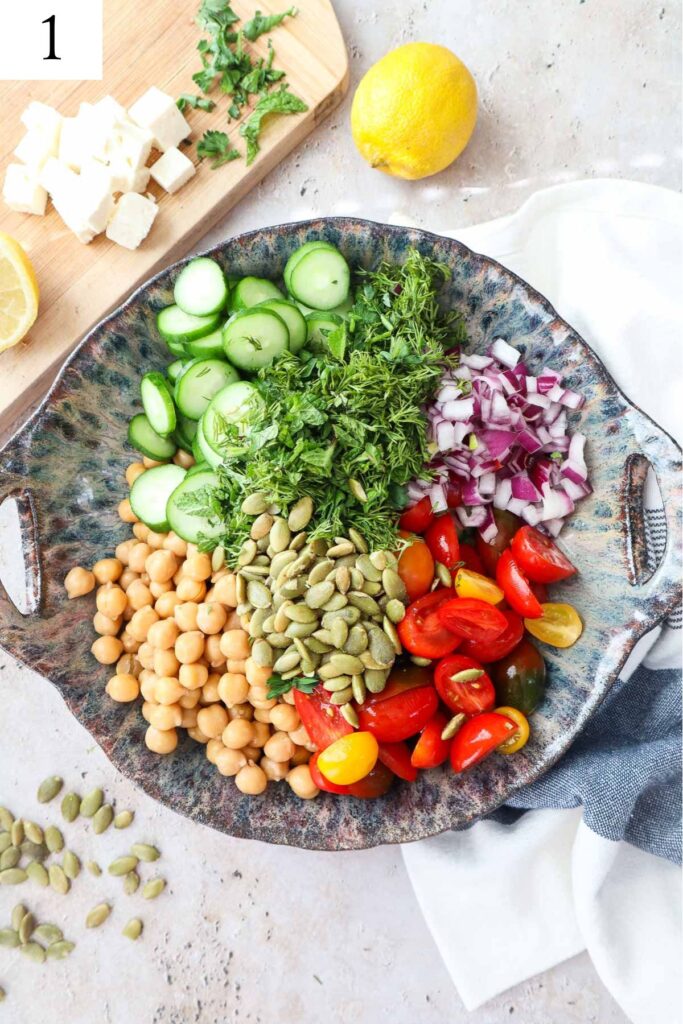 bowl with cucumber, chickpeas, tomatoes, onion, and herbs.