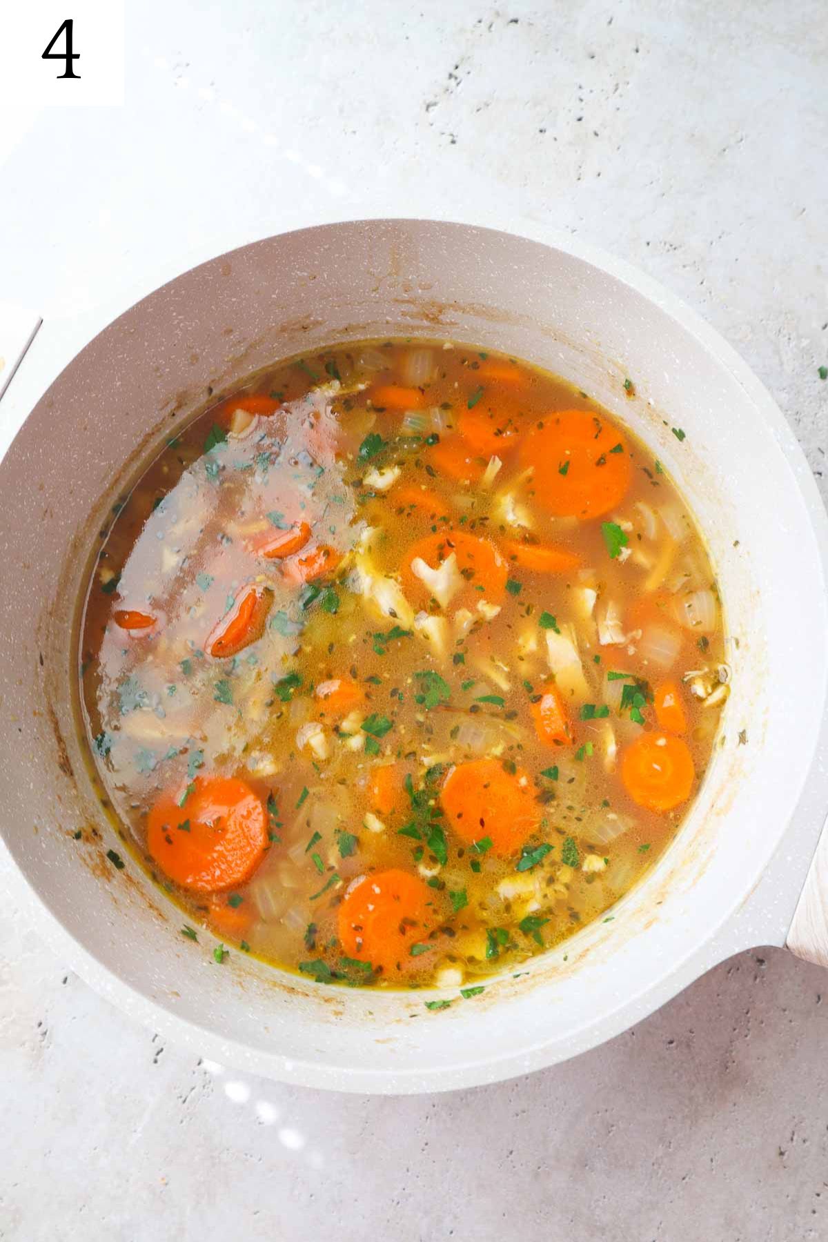pot with chicken noodle soup without celery topped with parsley.