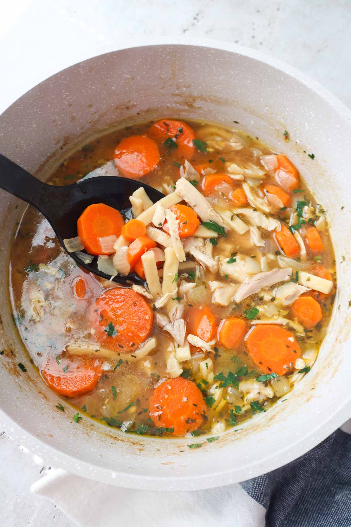 bowl with chicken noodle soup without celery topped with parsley.