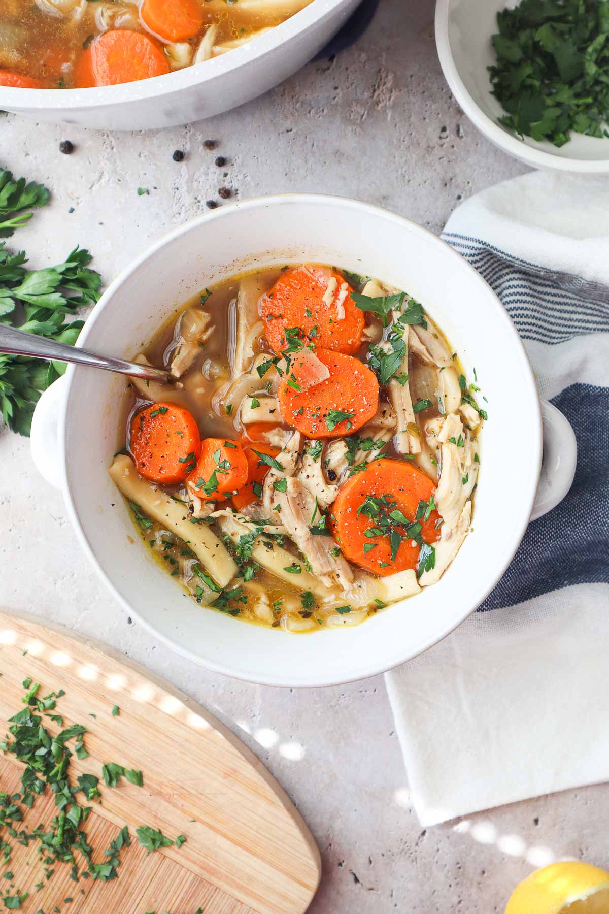 bowl with chicken noodle soup without celery topped with parsley.