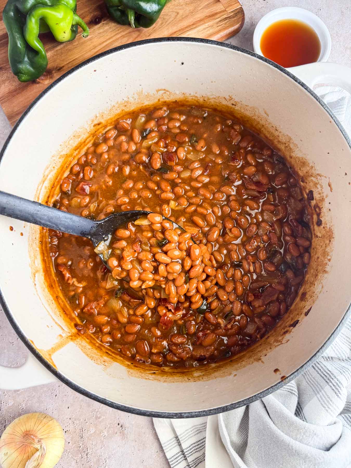 dutch oven with spoon scooping maple baked beans.