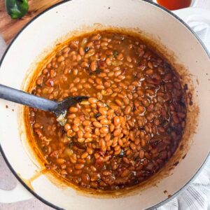 dutch oven with spoon scooping maple baked beans.