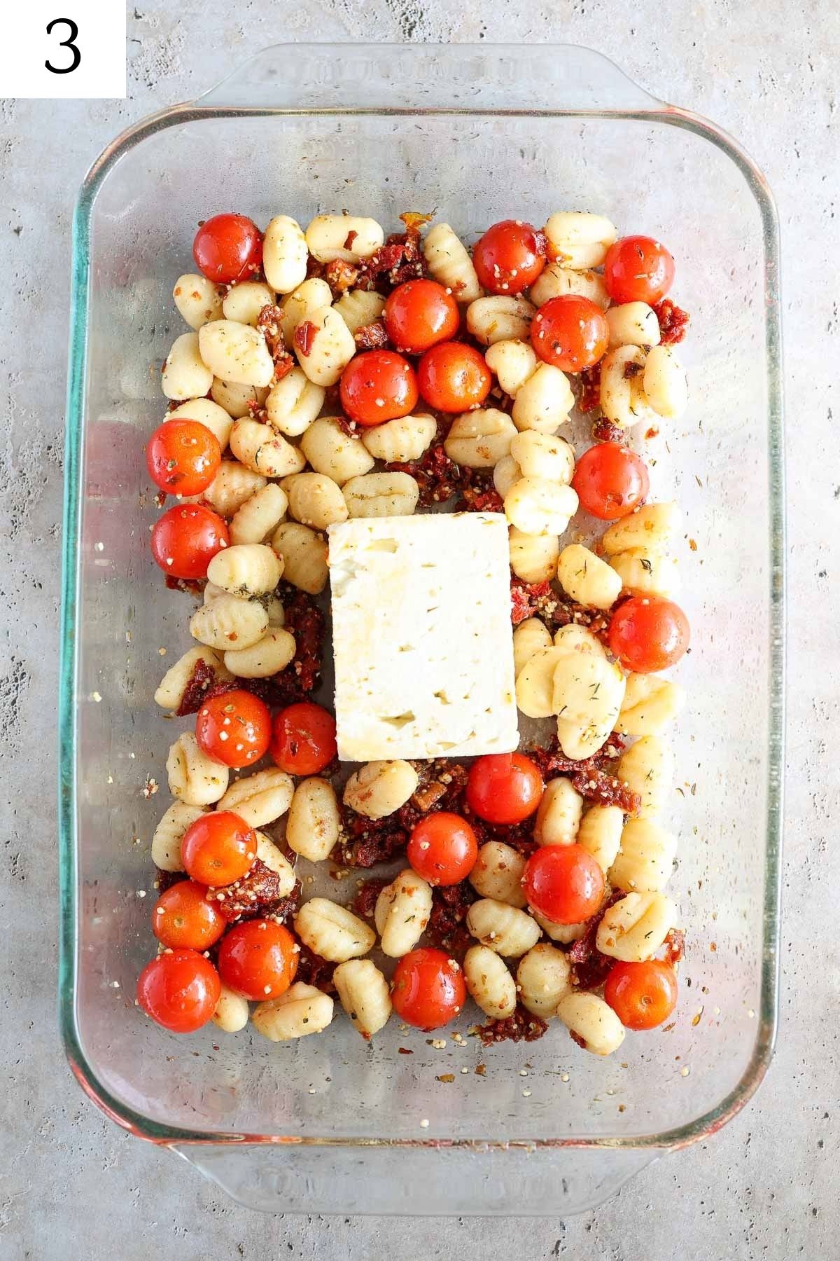 glass baking dish with gnocchi, tomatoes, feta, and seasonings.
