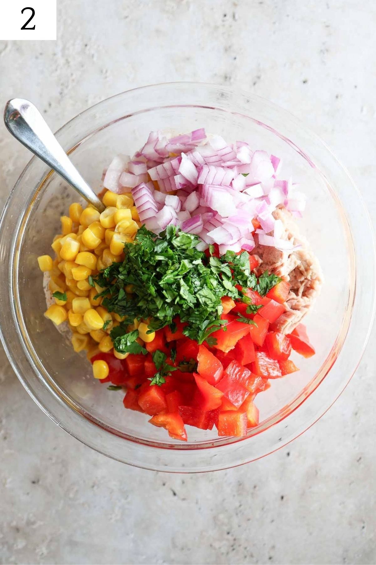 glass bowl with corn, onion, bell pepper, tuna, and cilantro.