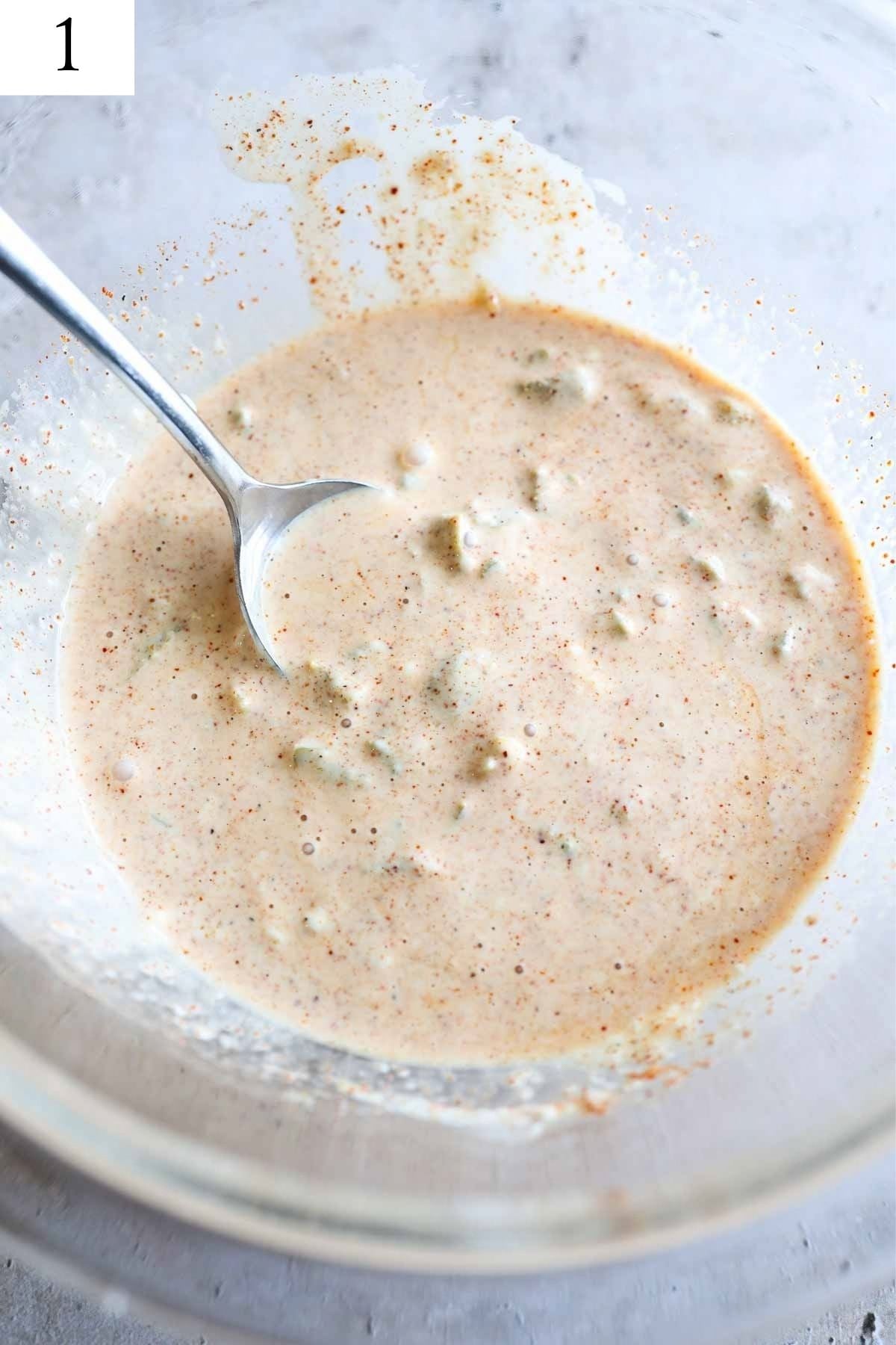 glass bowl with mayo, seasonings, and jalapenos mixed together.